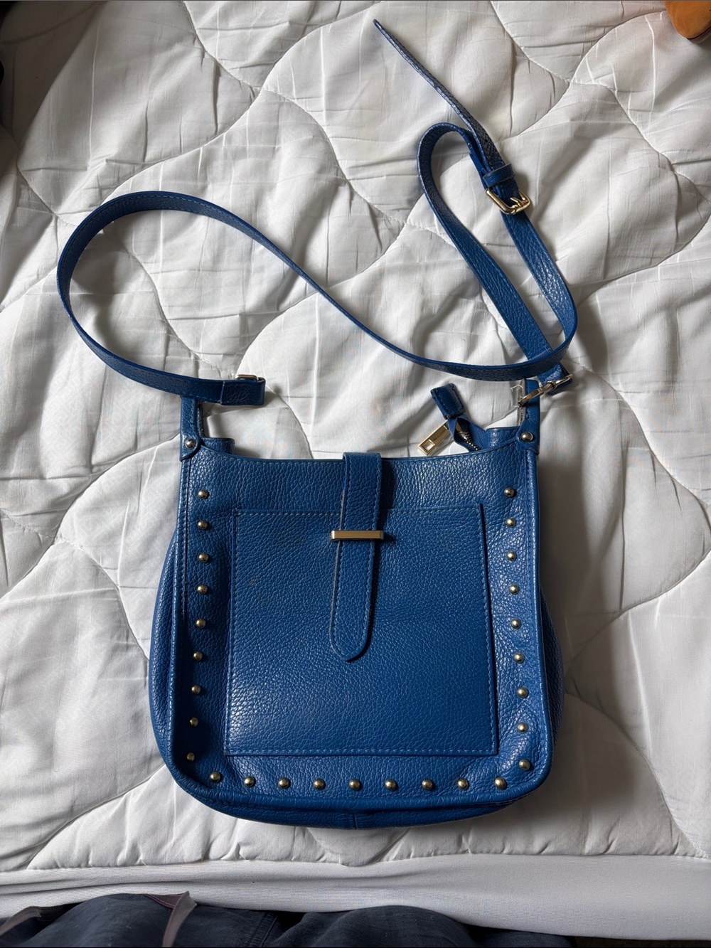 Genuine leather. 
Pebbled Blue Stud-Trim Crossbody Bag with Front Flap